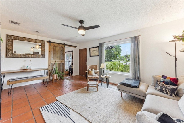3409 Kay St, Austin, TX 78702 - living room with a barn door, tile patterned flooring, ceiling fan, a textured ceiling, and baseboards