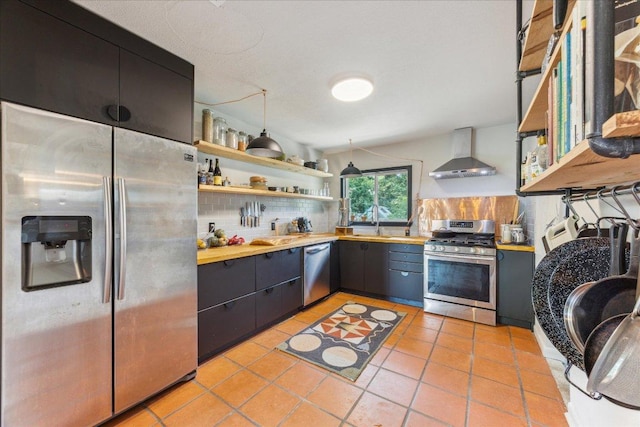 3409 Kay St, Austin, TX 78702 - kitchen with appliances with stainless steel finishes, wall chimney range hood, open shelves, tasteful backsplash, and light tile patterned flooring
