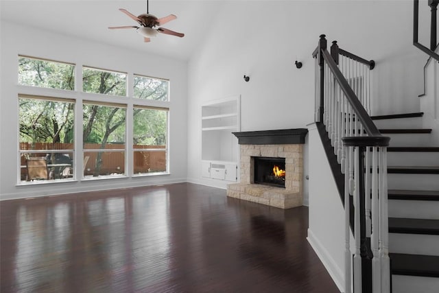 7921 Davis Mountain Pass, Austin, TX 78726 - unfurnished living room featuring built in shelves, ceiling fan, a stone fireplace, stairway, and wood finished floors