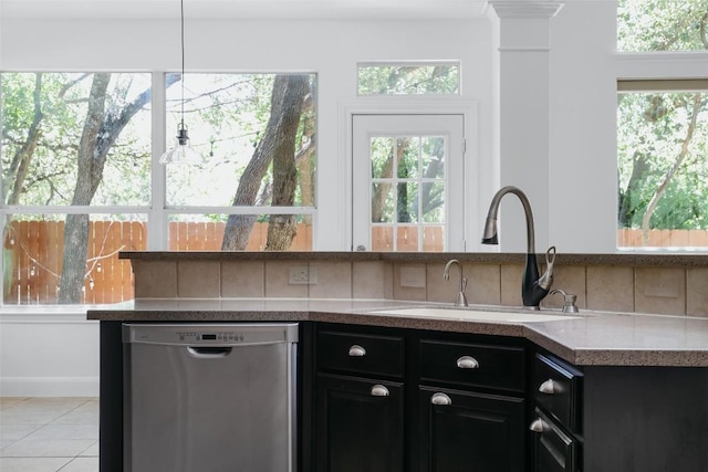 7921 Davis Mountain Pass, Austin, TX 78726 - kitchen with stainless steel dishwasher, a sink, dark cabinetry, light tile patterned floors, and healthy amount of natural light
