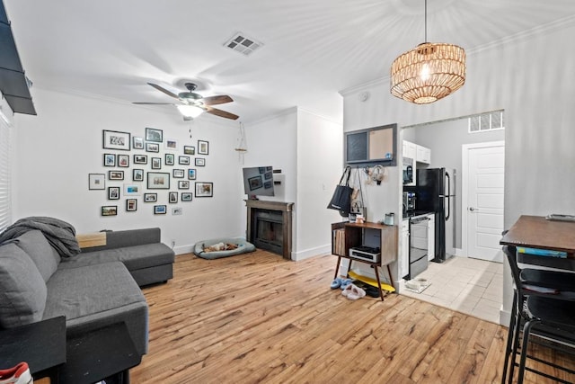 2804 Rio Grande St Unit 206, Austin, TX 78705 - living area with a fireplace, crown molding, light wood-style floors, a ceiling fan, and a chandelier