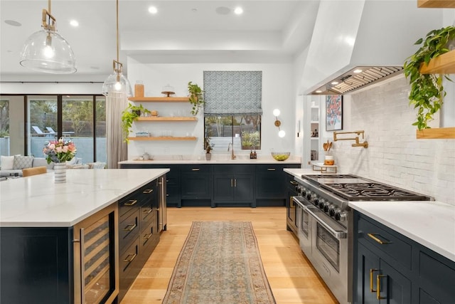 4901 Southcrest Dr, Austin, TX 78746 - kitchen featuring double oven range, beverage cooler, wall chimney exhaust hood, light wood finished floors, and decorative backsplash