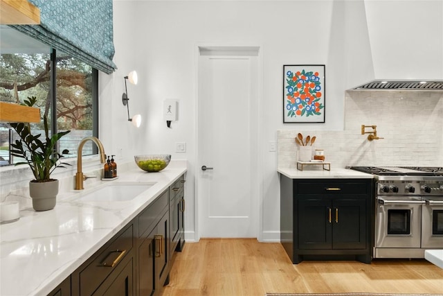 4901 Southcrest Dr, Austin, TX 78746 - bar featuring range with two ovens, wall chimney range hood, a sink, decorative backsplash, and light wood-style flooring