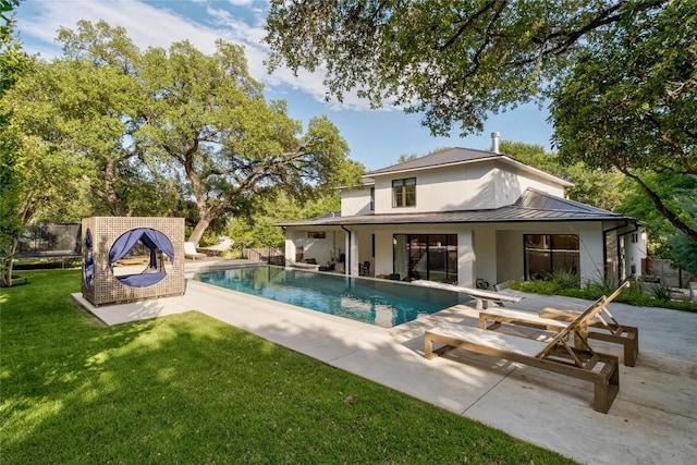 4901 Southcrest Dr, Austin, TX 78746 - back of property with a standing seam roof, a patio area, a lawn, metal roof, and stucco siding