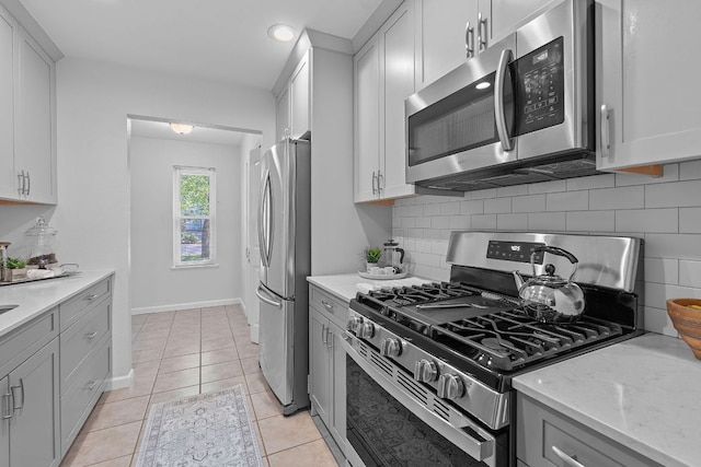2804 Bushnell Dr, Austin, TX 78745 - kitchen featuring appliances with stainless steel finishes, tasteful backsplash, light stone countertops, and light tile patterned floors