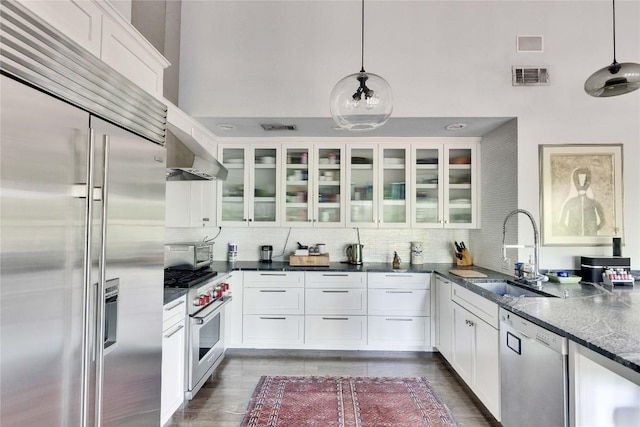 2602 Rollingwood Dr, Rollingwood, TX 78746 - kitchen featuring high quality appliances, a sink, wall chimney range hood, glass insert cabinets, and a high ceiling