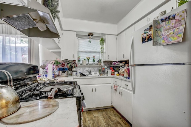 8505 Dryfield Dr, Austin, TX 78758 - kitchen with freestanding refrigerator, black gas stove, light countertops, and under cabinet range hood