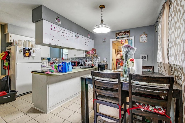 8505 Dryfield Dr, Austin, TX 78758 - kitchen with freestanding refrigerator, light tile patterned floors, a peninsula, tasteful backsplash, and decorative light fixtures