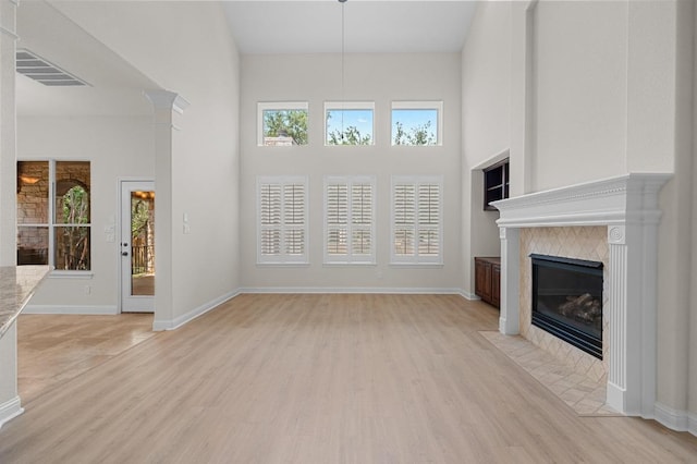 12304 Buvana Dr, Austin, TX 78739 - unfurnished living room with a towering ceiling, light wood-type flooring, a tile fireplace, and baseboards