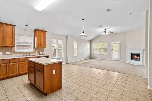 117 N Maplewood, Kyle, TX 78640 - kitchen with brown cabinets, open floor plan, light countertops, a ceiling fan, and light colored carpet