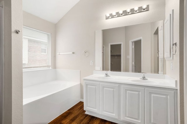 117 N Maplewood, Kyle, TX 78640 - bathroom featuring vaulted ceiling, a bath, double vanity, and wood finished floors