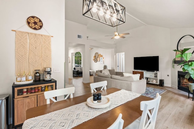 215 Crystal Knoll Blvd, Georgetown, TX 78626 - dining area featuring light wood-type flooring, a ceiling fan, baseboards, a glass covered fireplace, and high vaulted ceiling