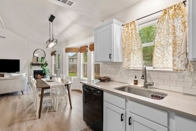 215 Crystal Knoll Blvd, Georgetown, TX 78626 - kitchen featuring black dishwasher, a sink, tasteful backsplash, light countertops, and a lit fireplace