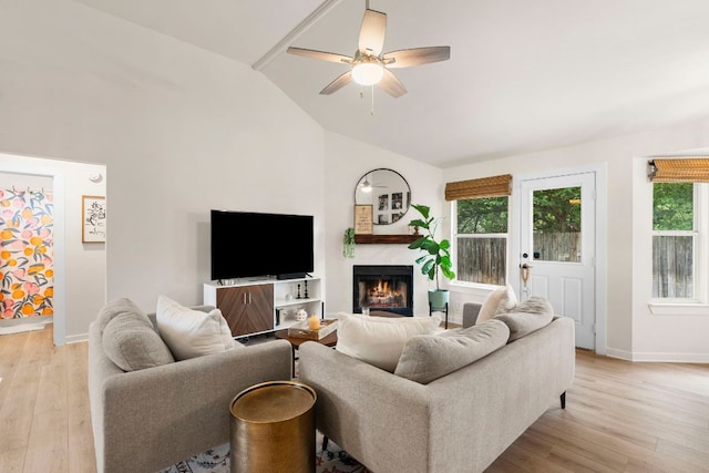 215 Crystal Knoll Blvd, Georgetown, TX 78626 - living room featuring lofted ceiling, light wood-type flooring, a ceiling fan, a lit fireplace, and baseboards