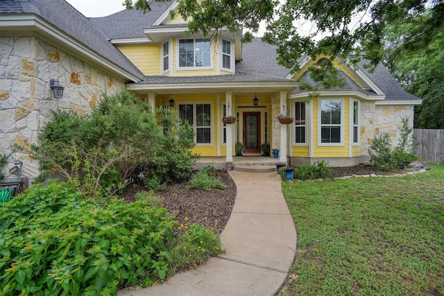 233 Maple Leaf Trl, Elgin, TX 78621 - view of front of house featuring stone siding, a shingled roof, covered porch, and a front lawn