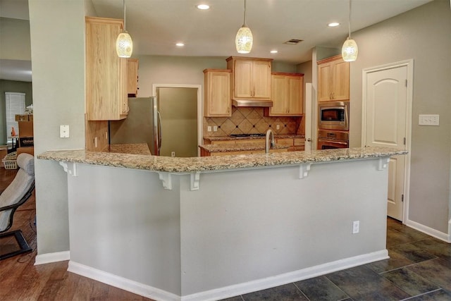 233 Maple Leaf Trl, Elgin, TX 78621 - kitchen with stainless steel appliances, light brown cabinetry, a peninsula, under cabinet range hood, and tasteful backsplash