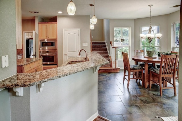 233 Maple Leaf Trl, Elgin, TX 78621 - kitchen featuring appliances with stainless steel finishes, light brown cabinetry, a kitchen bar, plenty of natural light, and recessed lighting