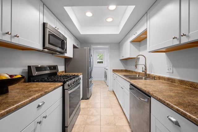 7607 Whispering Winds Dr, Austin, TX 78745 - kitchen featuring stainless steel appliances, a sink, washer and dryer, recessed lighting, and a tray ceiling
