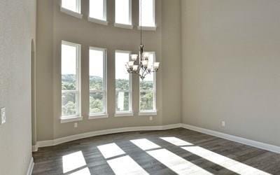 4720 Napoli Shore Dr, Leander, TX 78641 - unfurnished dining area featuring dark wood-style floors, a chandelier, baseboards, and a high ceiling