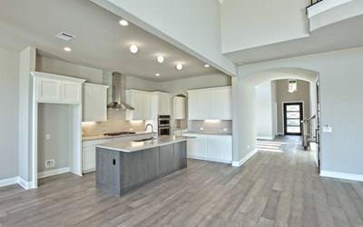 4720 Napoli Shore Dr, Leander, TX 78641 - kitchen with wall chimney exhaust hood, arched walkways, white cabinetry, baseboards, and recessed lighting