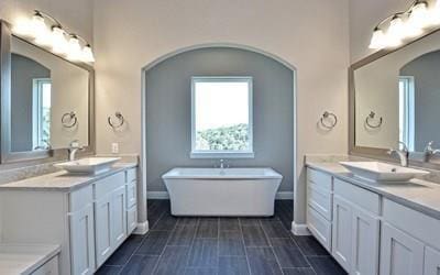 4720 Napoli Shore Dr, Leander, TX 78641 - bathroom featuring a soaking tub, two vanities, and baseboards