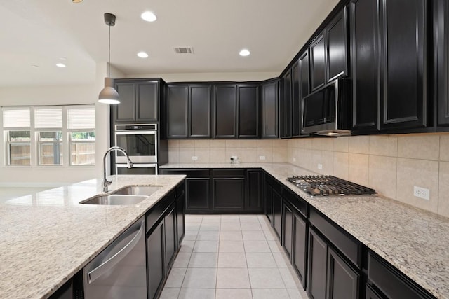 7109 Bargello Pl, Round Rock, TX 78665 - kitchen featuring dark cabinets, stainless steel appliances, a sink, light stone countertops, and recessed lighting