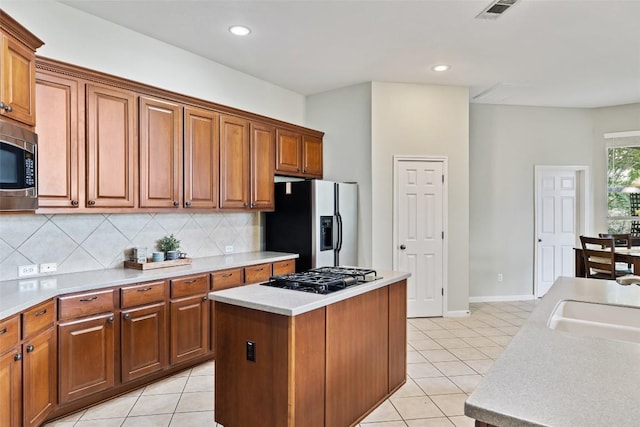 10129 Brimfield Dr, Austin, TX 78726 - kitchen featuring stainless steel appliances, light tile patterned floors, a center island, decorative backsplash, and brown cabinets