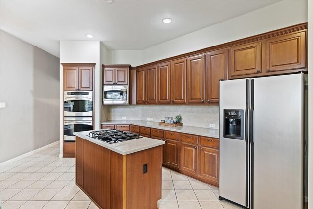 10129 Brimfield Dr, Austin, TX 78726 - kitchen featuring stainless steel appliances, light tile patterned floors, light countertops, a center island, and decorative backsplash