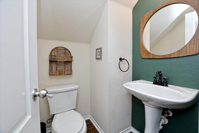 510 W Metcalfe St, Hutto, TX 78634 - half bathroom with lofted ceiling, toilet, a textured wall, and wood finished floors