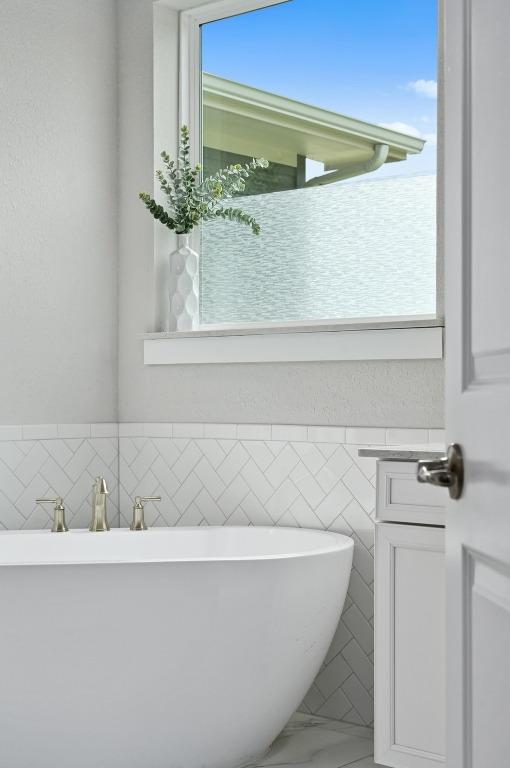467 Cortaro Dr, Dripping Springs, TX 78620 - bathroom with a soaking tub, marble finish flooring, and tile walls