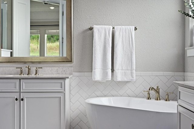 467 Cortaro Dr, Dripping Springs, TX 78620 - bathroom with vanity, a soaking tub, tile walls, and a textured wall