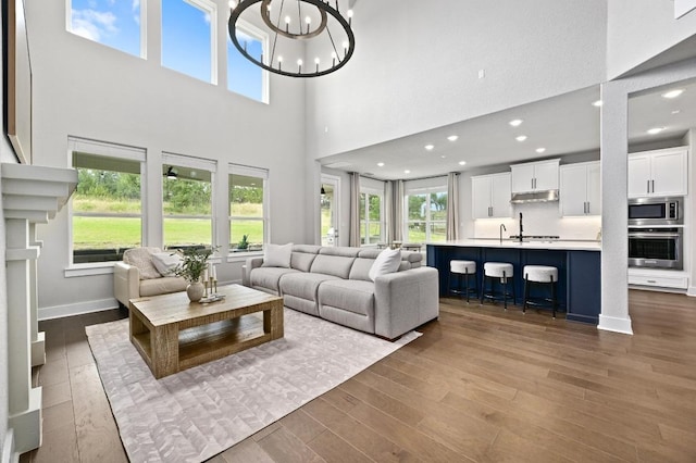 467 Cortaro Dr, Dripping Springs, TX 78620 - living room featuring healthy amount of natural light, wood finished floors, a chandelier, a high ceiling, and recessed lighting