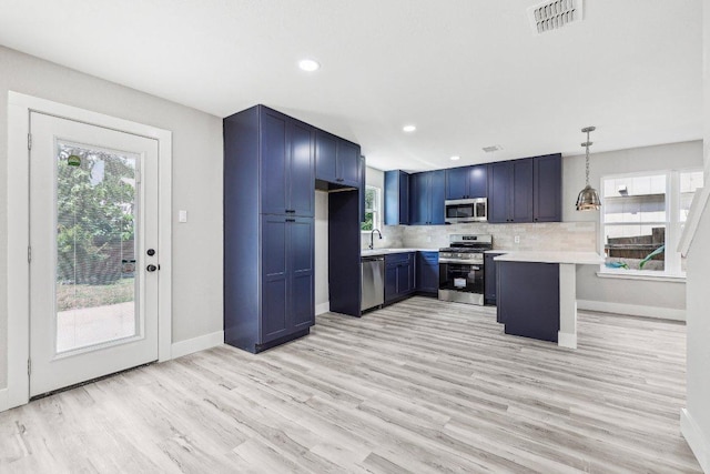8804 Ravello Pass, Austin, TX 78749 - kitchen featuring appliances with stainless steel finishes, light countertops, blue cabinetry, light wood-style flooring, and a peninsula