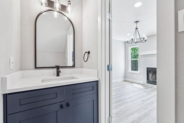 8804 Ravello Pass, Austin, TX 78749 - bathroom featuring a chandelier, vanity, wood finished floors, and a glass covered fireplace