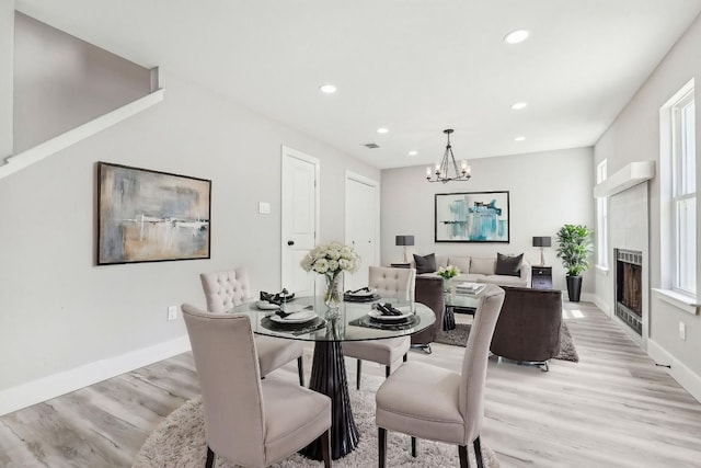 8804 Ravello Pass, Austin, TX 78749 - dining space with light wood finished floors, a chandelier, recessed lighting, baseboards, and a tiled fireplace