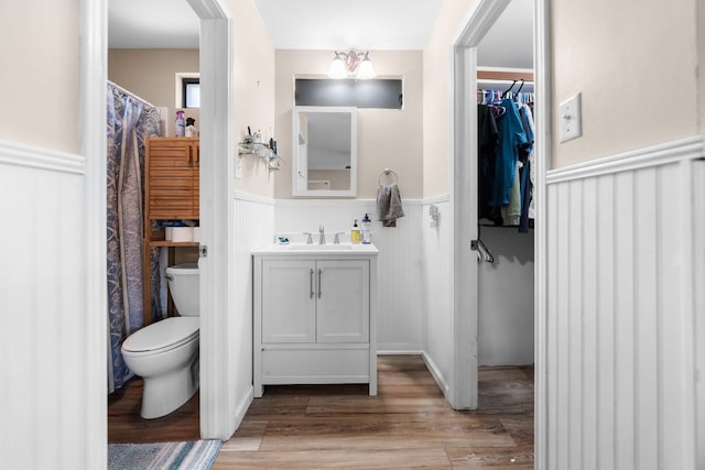 6807 Bill Hughes Rd, Austin, TX 78745 - full bath featuring a wainscoted wall, toilet, vanity, wood finished floors, and a spacious closet