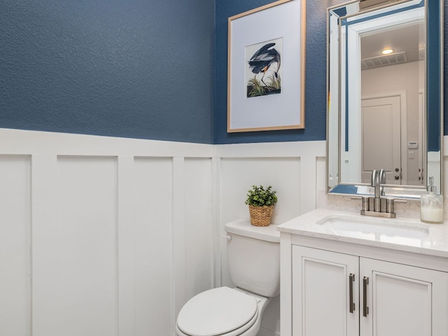 108 Brantley Lake Ln, Georgetown, TX 78628 - half bath featuring toilet, vanity, a decorative wall, and wainscoting