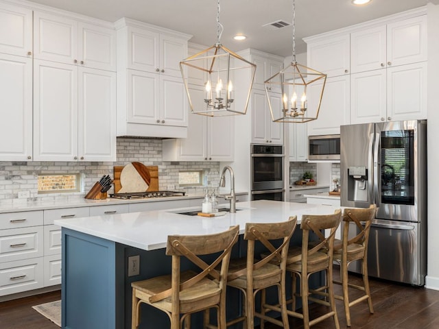 108 Brantley Lake Ln, Georgetown, TX 78628 - kitchen featuring appliances with stainless steel finishes, a chandelier, dark wood-type flooring, a center island with sink, and recessed lighting
