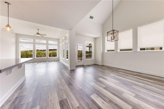 748 Hazy Hills Loop, Dripping Springs, TX 78620 - unfurnished living room featuring healthy amount of natural light, ceiling fan, wood finished floors, baseboards, and high vaulted ceiling