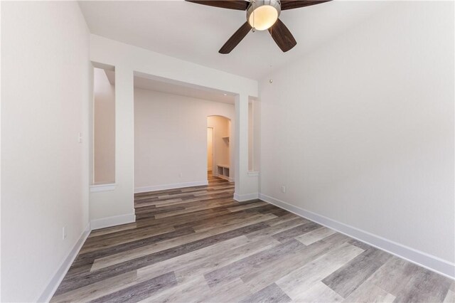 748 Hazy Hills Loop, Dripping Springs, TX 78620 - spare room featuring a ceiling fan, arched walkways, wood finished floors, and baseboards
