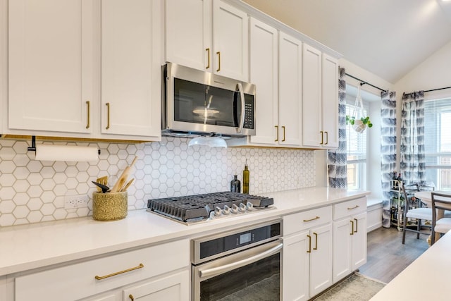 111 Blackwell Ln, Kyle, TX 78640 - kitchen featuring stainless steel appliances, light countertops, white cabinetry, lofted ceiling, and wood finished floors