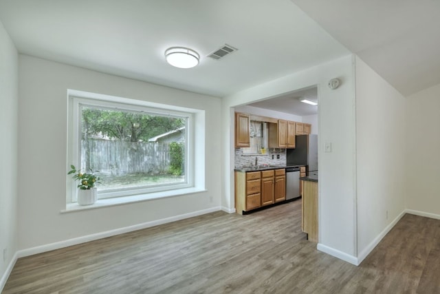 9001 Lodge Ct, Austin, TX 78758 - kitchen with stainless steel appliances, dark countertops, light wood finished floors, backsplash, and brown cabinets