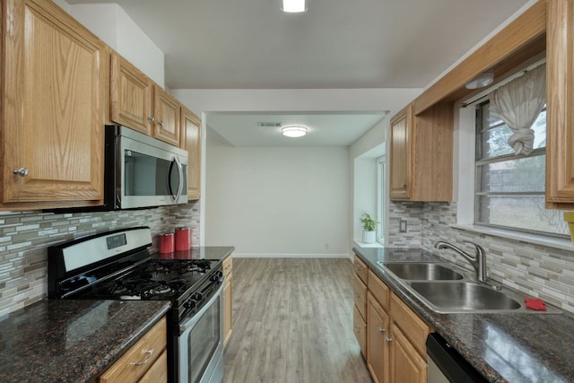 9001 Lodge Ct, Austin, TX 78758 - kitchen with appliances with stainless steel finishes, backsplash, light wood finished floors, and dark stone counters