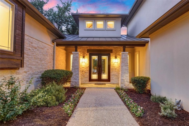 7116 Greenshores Dr, Austin, TX 78730 - view of exterior entry featuring a standing seam roof, stone siding, french doors, metal roof, and stucco siding
