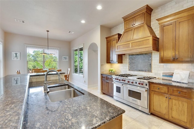 7116 Greenshores Dr, Austin, TX 78730 - kitchen with range with two ovens, a sink, custom exhaust hood, tasteful backsplash, and dark stone counters