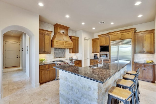 7116 Greenshores Dr, Austin, TX 78730 - kitchen with a sink, built in appliances, tasteful backsplash, arched walkways, and brown cabinets