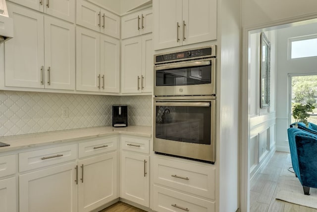 101 Peterson Ct, Austin, TX 78734 - kitchen featuring double oven, decorative backsplash, white cabinetry, and light stone countertops