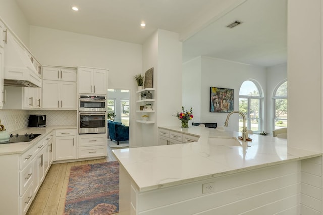 101 Peterson Ct, Austin, TX 78734 - kitchen featuring black electric stovetop, a peninsula, light stone countertops, tasteful backsplash, and white cabinets