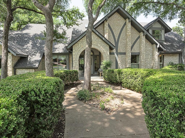1400 Pearl Cv, Round Rock, TX 78681 - tudor-style house with stone siding, covered porch, and a shingled roof