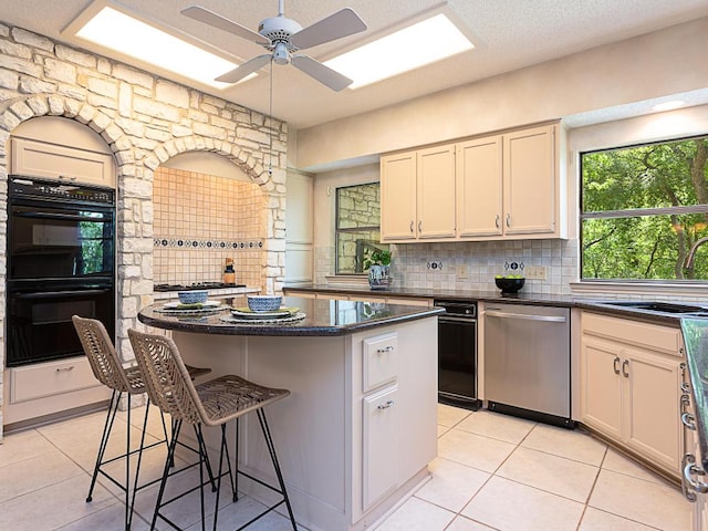 1400 Pearl Cv, Round Rock, TX 78681 - kitchen featuring stainless steel dishwasher, a center island, light tile patterned floors, and backsplash